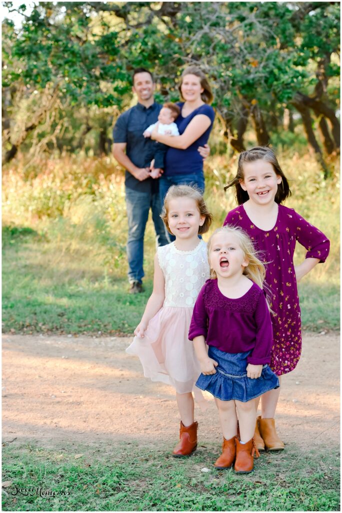 The little girls posing with mom, dad, and brother in the background.