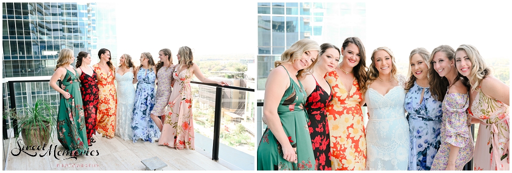 The bridesmaids wearing floral gowns and surrounding the bride.