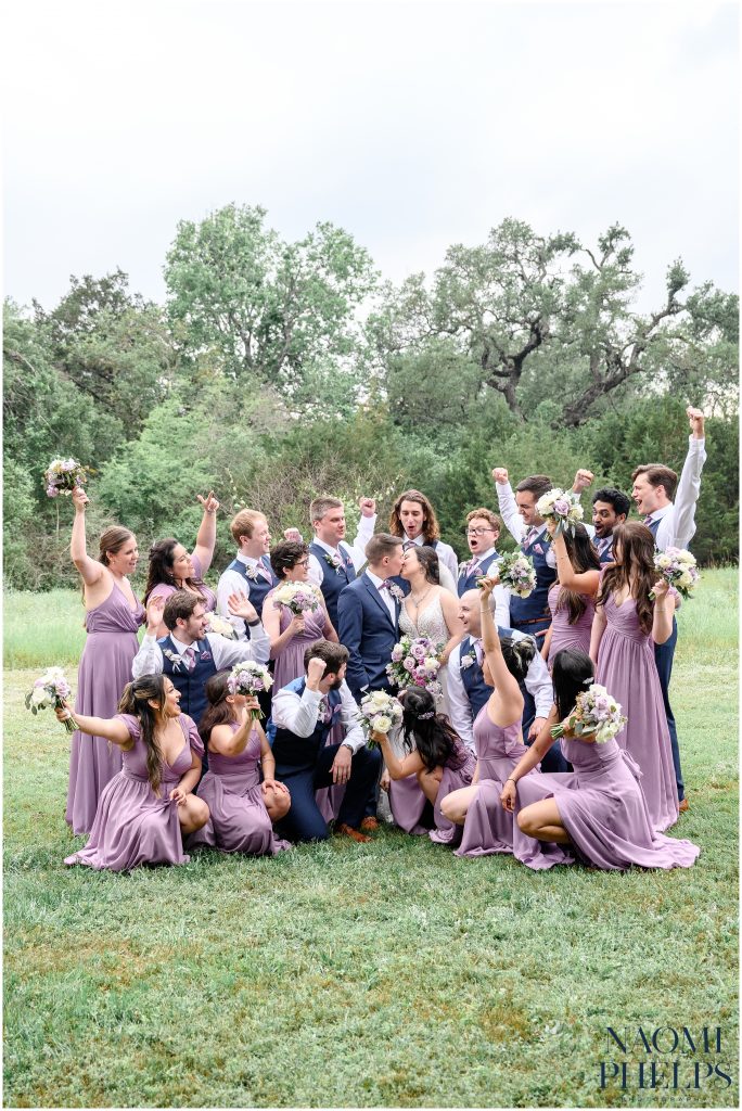 The wedding party wearing all purple cheering on the bride and groom.