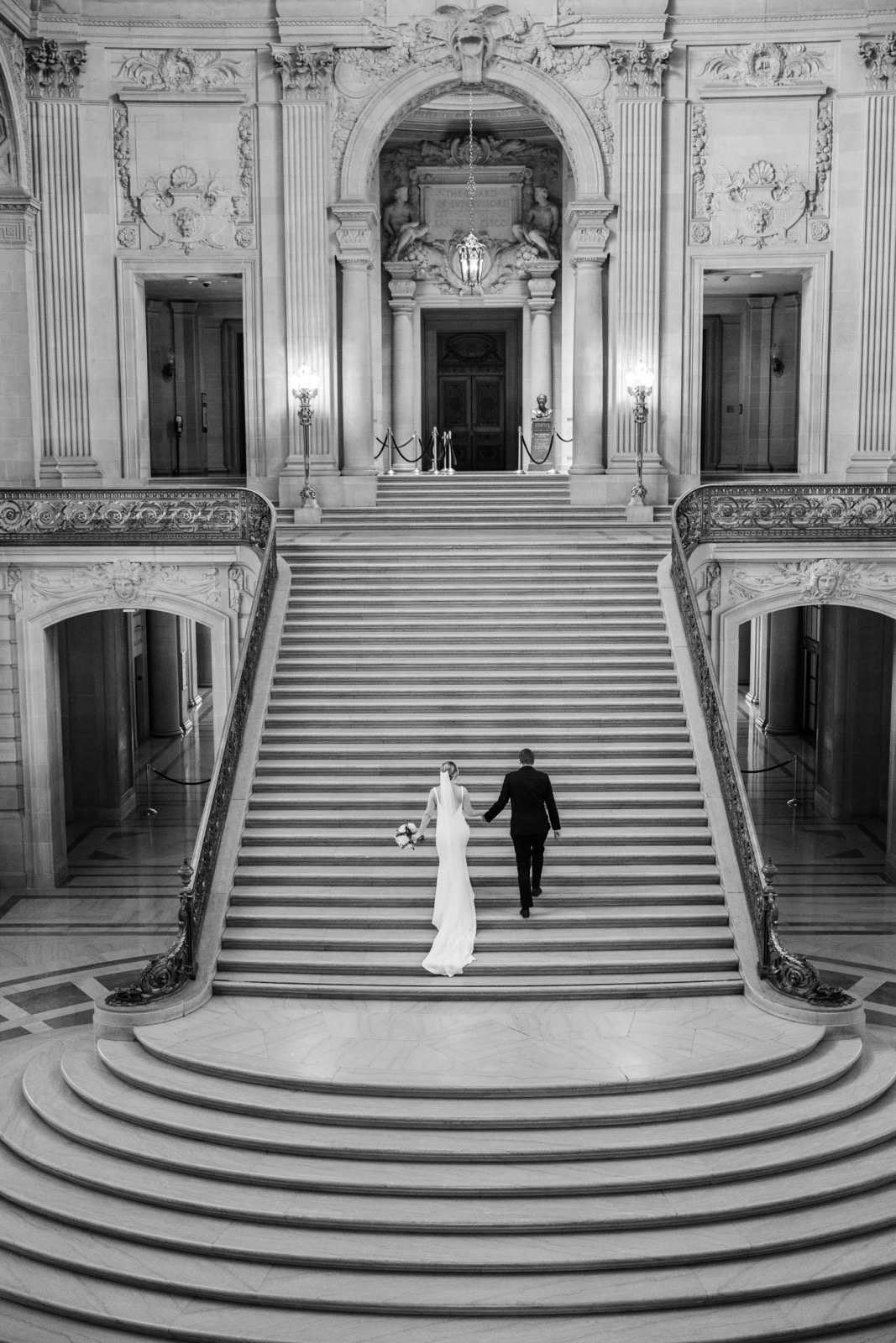 Couple walking up the stairs at the San Francisco City Hall Rotunda