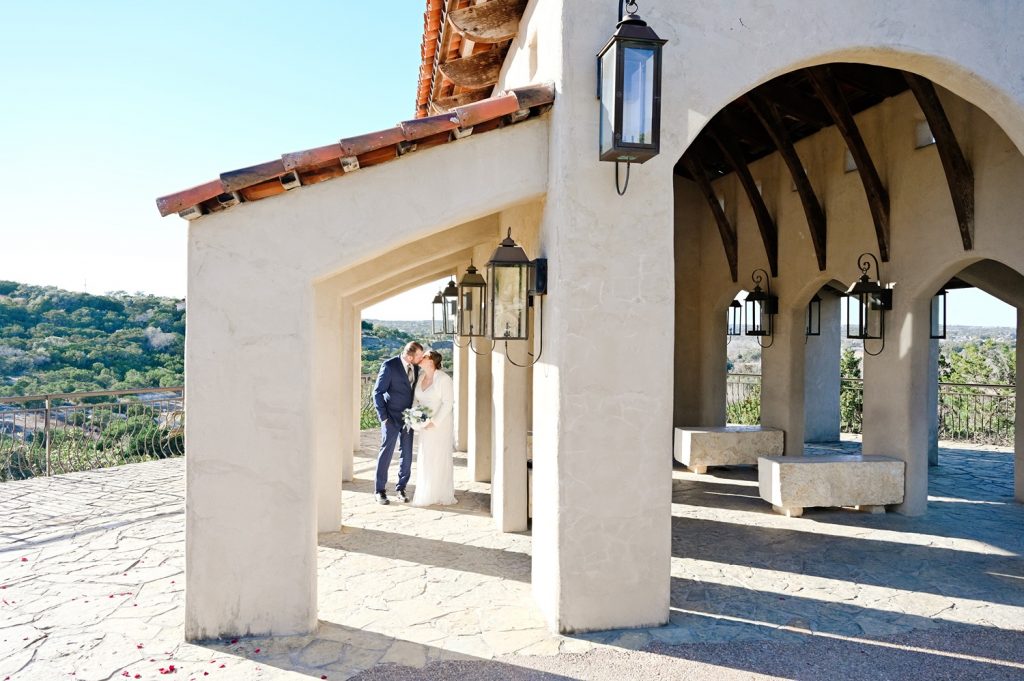 Newlyweds kissing at their historic wedding venue in Austin with unique architecture.