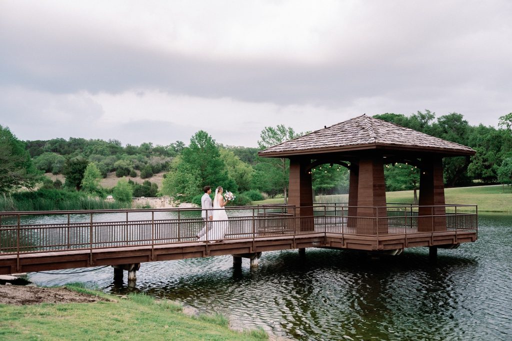 Couple walking to a waterfront terrace at their wedding venue near Austin TX.