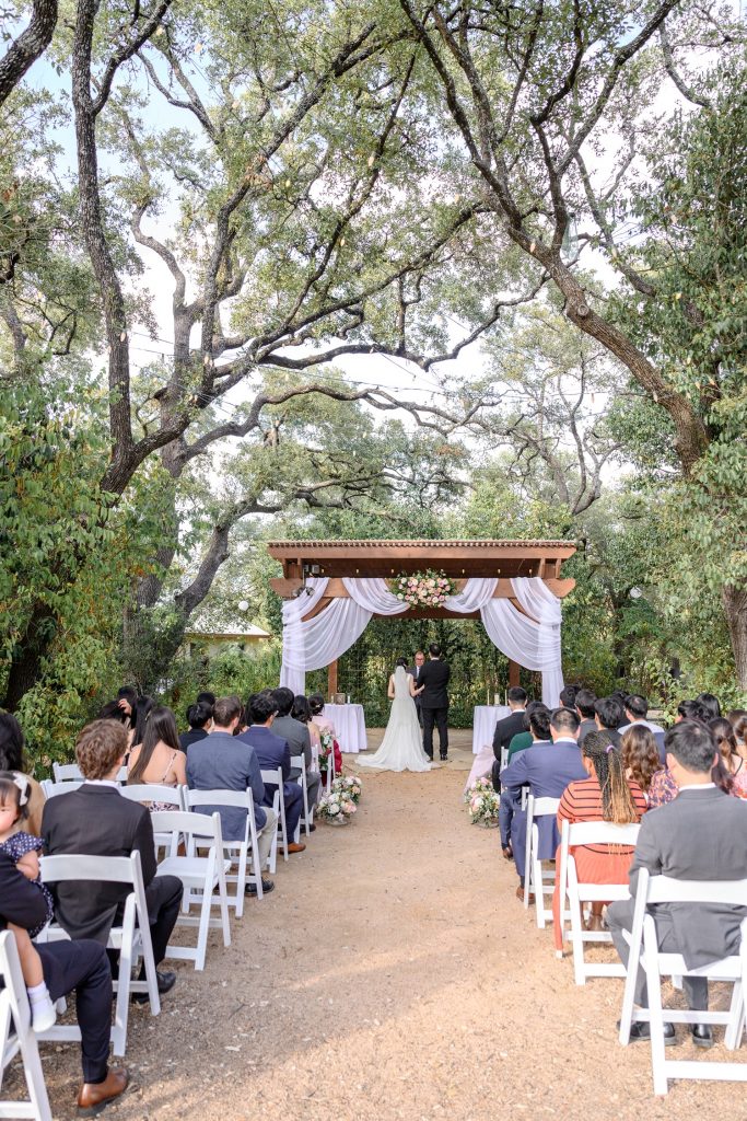 Couple exchanging vows in an outdoor wedding ceremony at Hudson Bend Ranch in Austin.