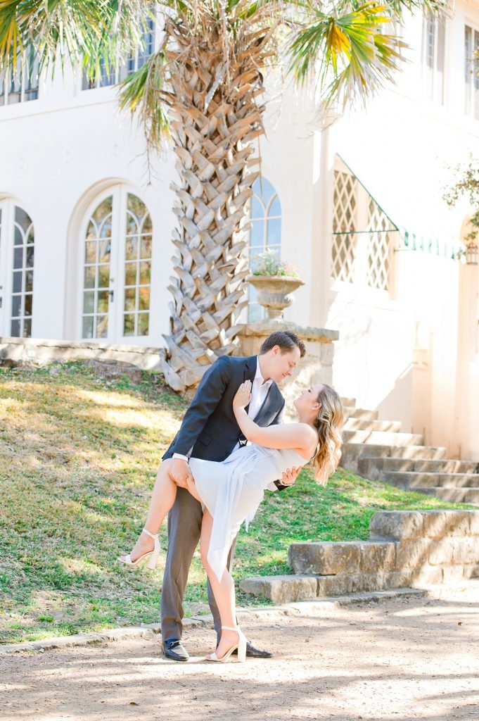 Man dipping his fiancée outside of Laguna Gloria for engagement photos in Austin TX.