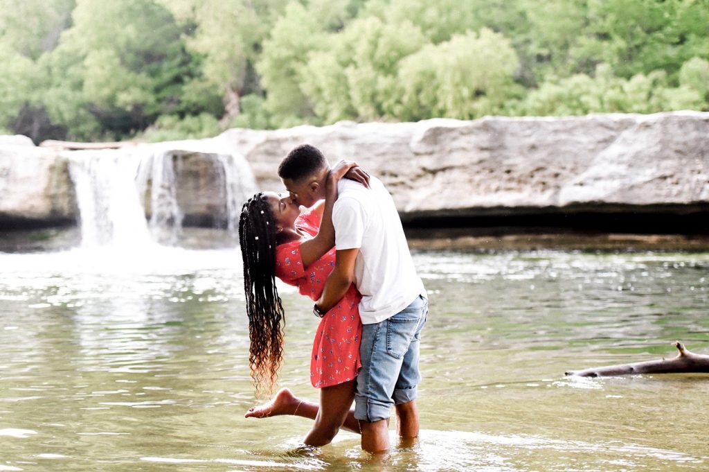 Engaged couple kissing in the water at McKinney Falls State Park.