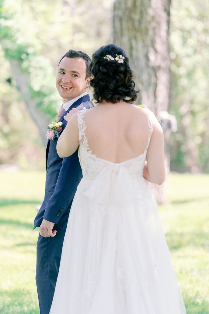 Bride tapping on groom's shoulder for a first look at Pecan Springs Ranch.