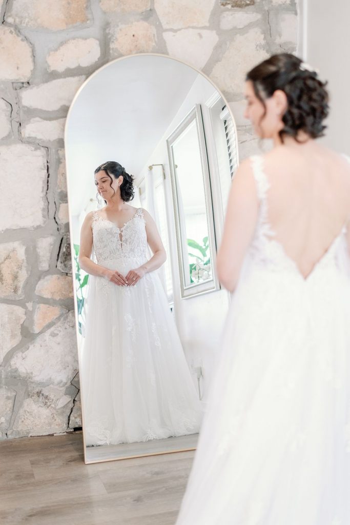 Austin bride getting ready in her wedding dress with a mirror showing her reflection.