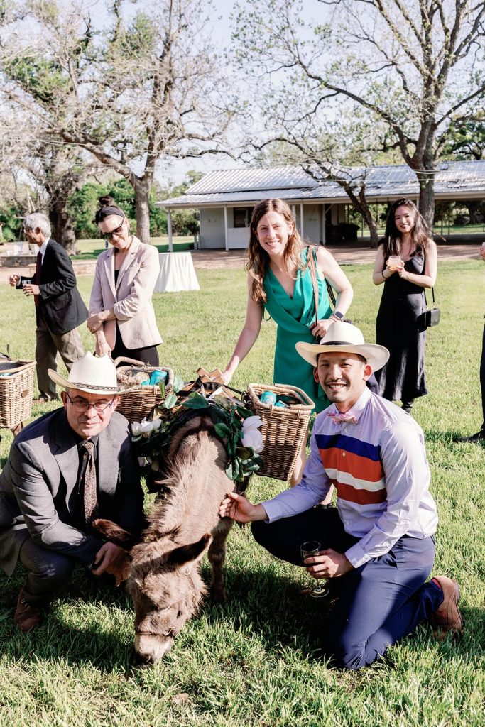 Wedding guests posing with a drink donkey at Pecan Springs Ranch wedding.
