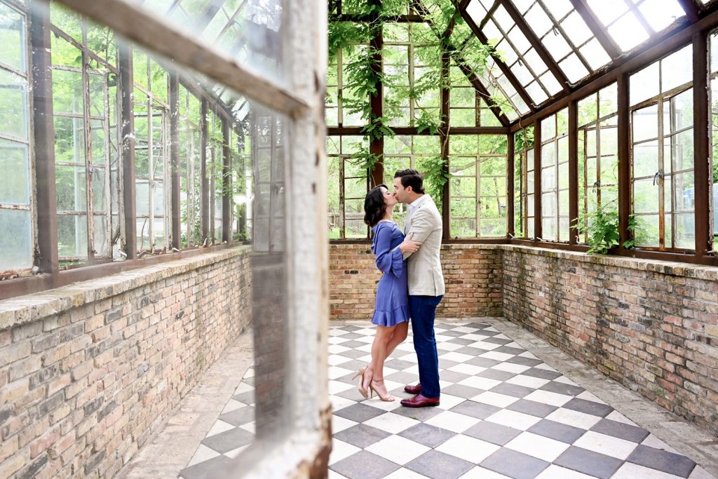Couple kissing in Sekrit Theater greenhouse for engagement photos in Austin, TX.