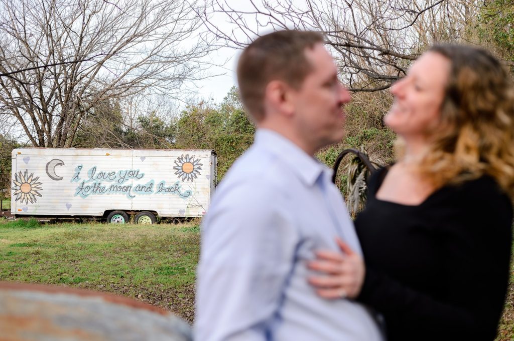 Couple smiling with a mural that sayd "I love you to the moon and back" at Sekrit Theater in Austin.