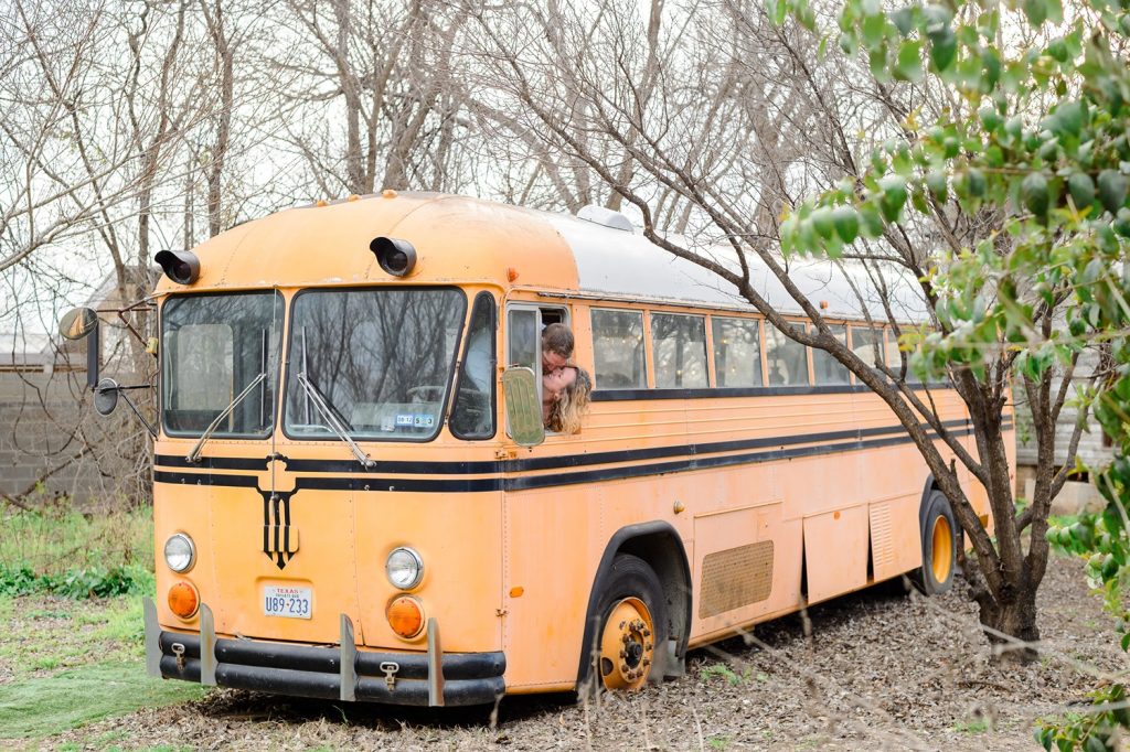 Newlyweds kissing with their heads out the window of the old school bus at Sekrit Theater.
