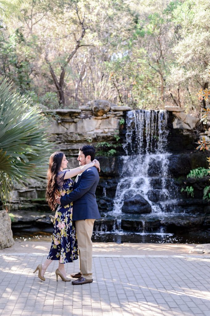 Man dancing with his fiancée in front of a waterfall at Zilker Botanical Garden.