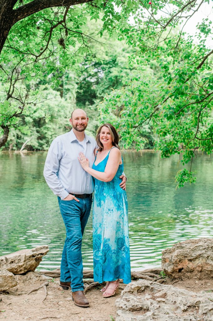 Engaged couple smiling next to the water at Zilker Metropolitan Park in Austin.