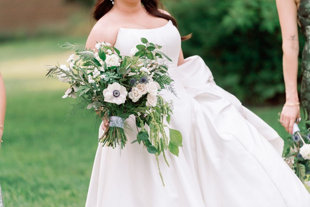 Bride holding a large bouquet of white flowers and greenery.