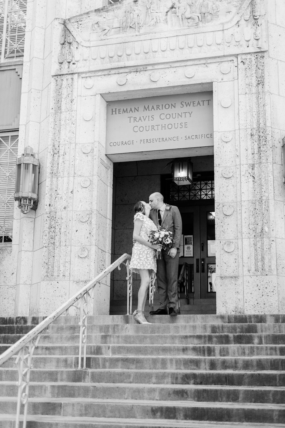 Newlywed couple kissing in front of Precinct 5 Courthouse