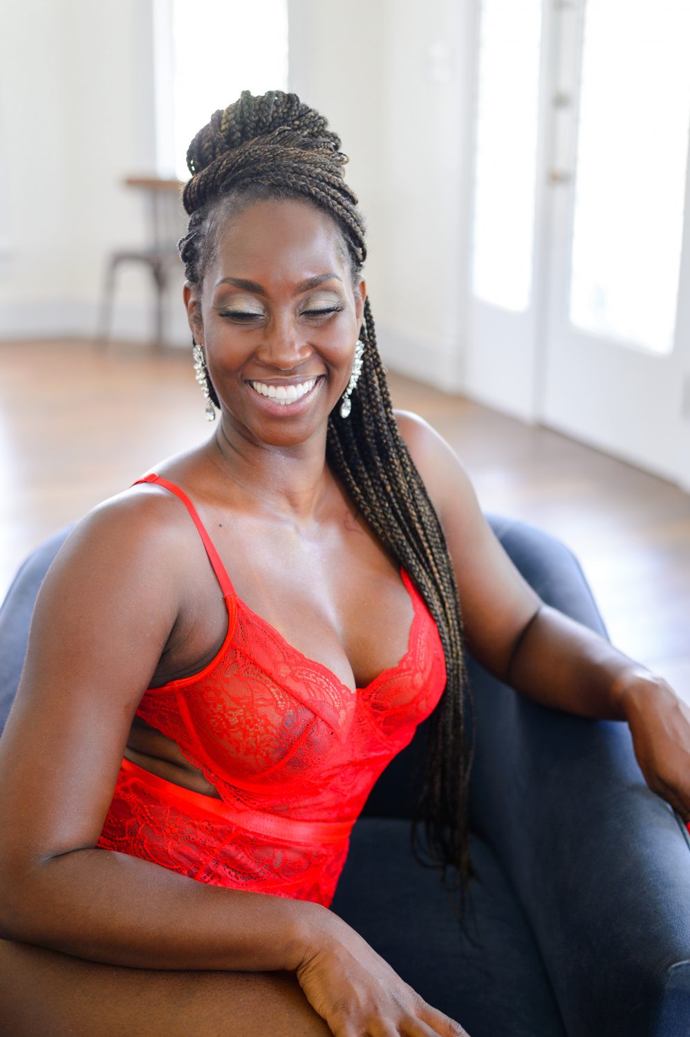 Black woman in red lingerie sitting on a black armchair for a boudoir photoshoot in Austin, TX