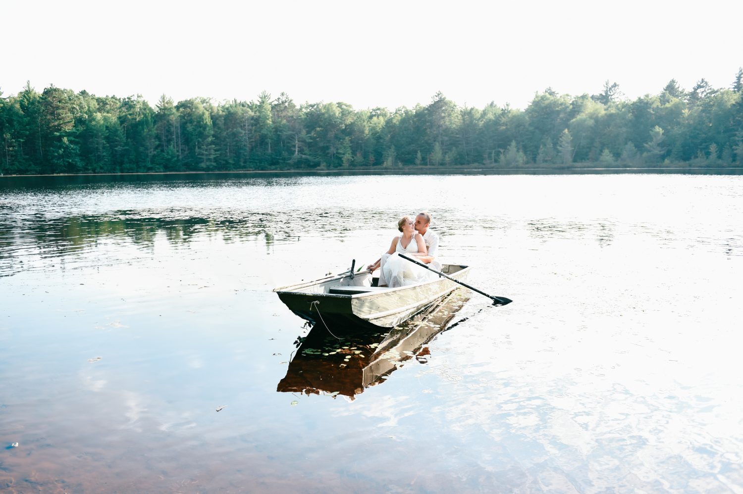 Bride and groom kissing on a rowboat on a lake in Wisconsin for a destination elopement