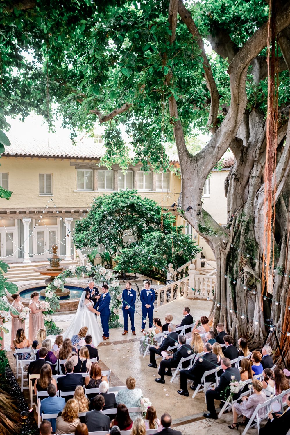 Destination wedding ceremony under large trees in front of a fountain in Boca Raton