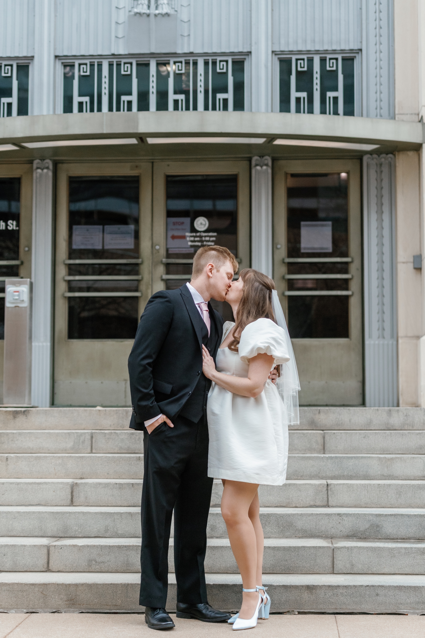 A bride and groom kiss in front of the Travis County Probate Courthouse