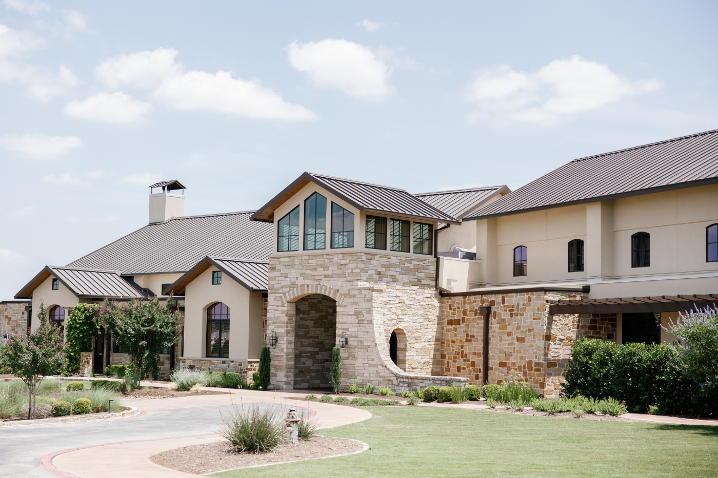 A wide view of Canyonwood Ridge, a large wedding venue with a stone entryway and dark, peaked roofs
