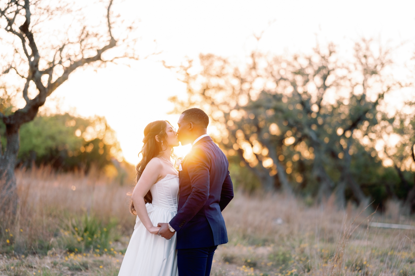 Golden sunlight shines around a bride and groom as they kiss